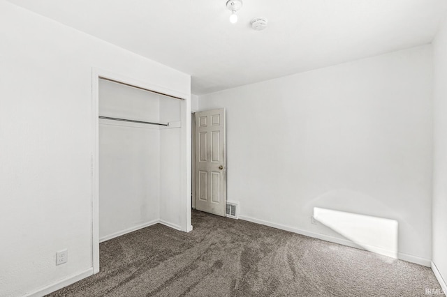 unfurnished bedroom with dark carpet and a closet