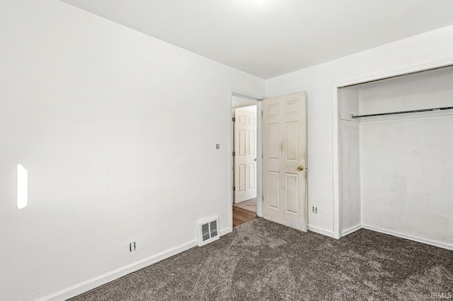 unfurnished bedroom featuring a closet and dark carpet