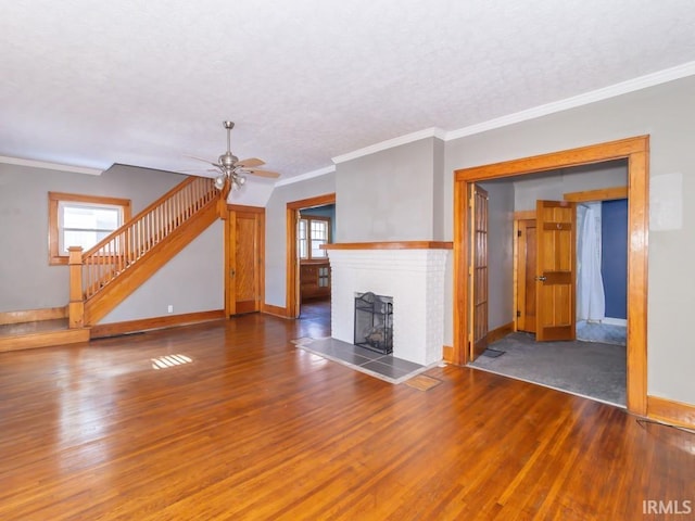 unfurnished living room with a fireplace, ornamental molding, ceiling fan, and dark wood-type flooring