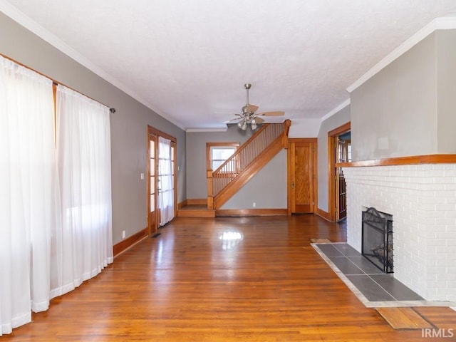 unfurnished living room featuring a brick fireplace, ornamental molding, ceiling fan, and dark wood-type flooring