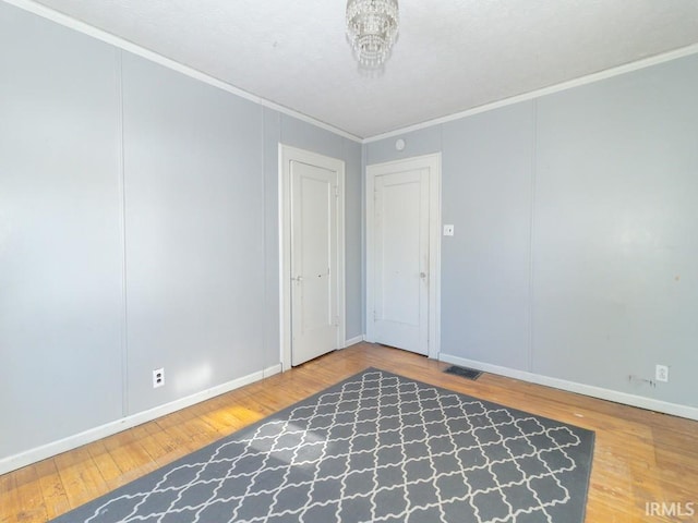 empty room with wood-type flooring and ornamental molding