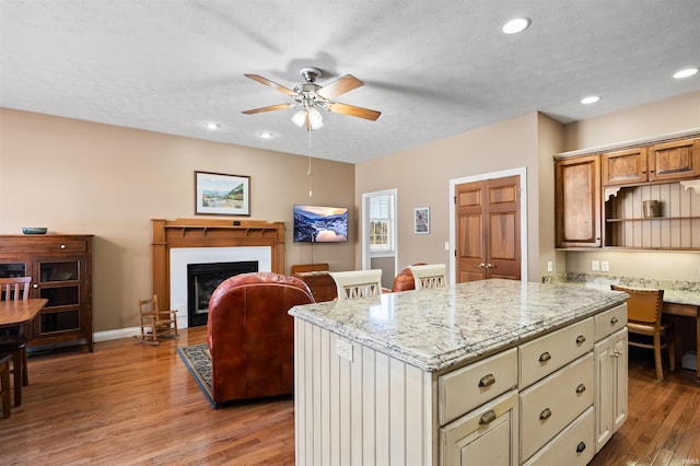 kitchen with a center island, ceiling fan, a textured ceiling, and light stone countertops