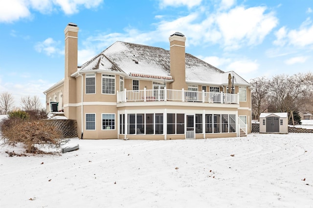 snow covered house with a balcony and a storage shed