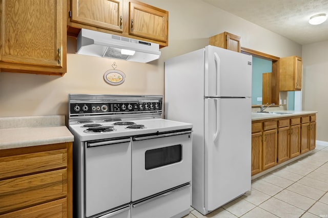 kitchen featuring white appliances, a textured ceiling, light tile patterned floors, and sink