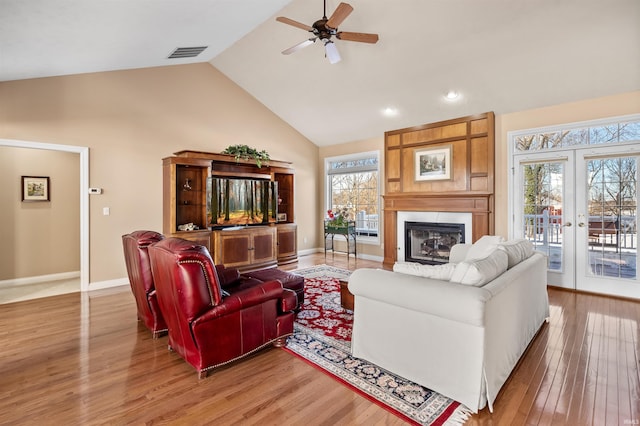 living room with a healthy amount of sunlight, french doors, a fireplace, and hardwood / wood-style flooring