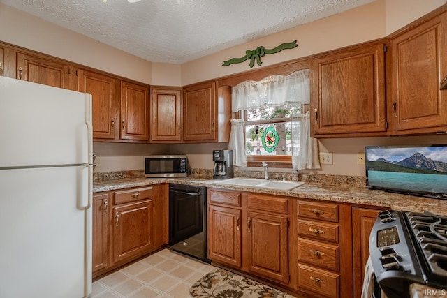 kitchen featuring light stone counters, stainless steel appliances, a textured ceiling, and sink