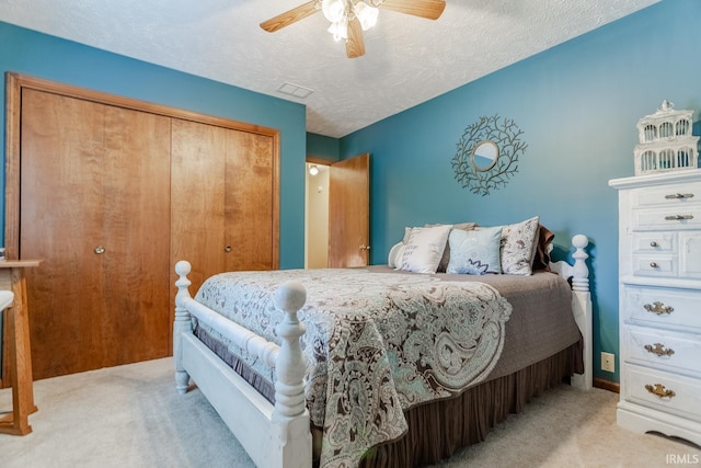 bedroom with a closet, light carpet, a textured ceiling, and ceiling fan