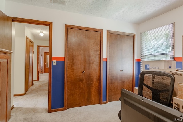 carpeted bedroom with a textured ceiling and two closets