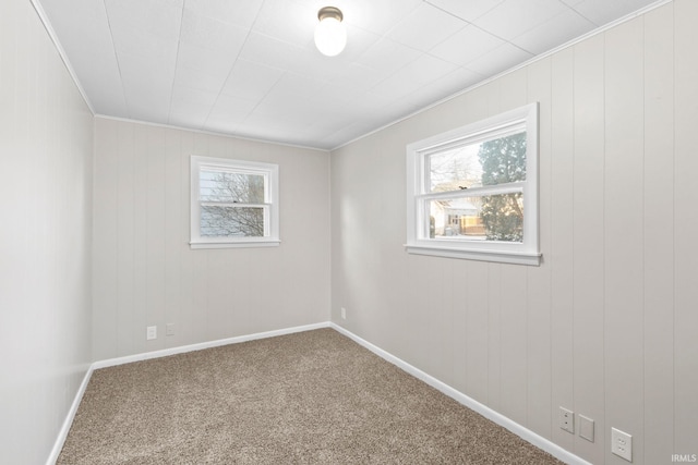 empty room with a healthy amount of sunlight, ornamental molding, and carpet flooring