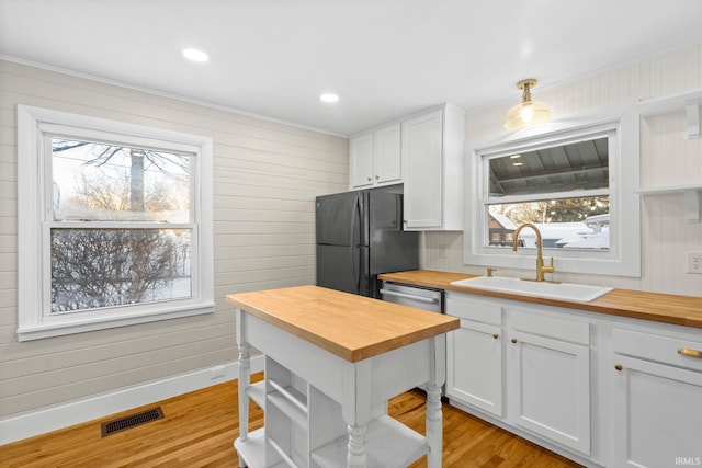 kitchen with sink, white cabinetry, hanging light fixtures, and wood counters