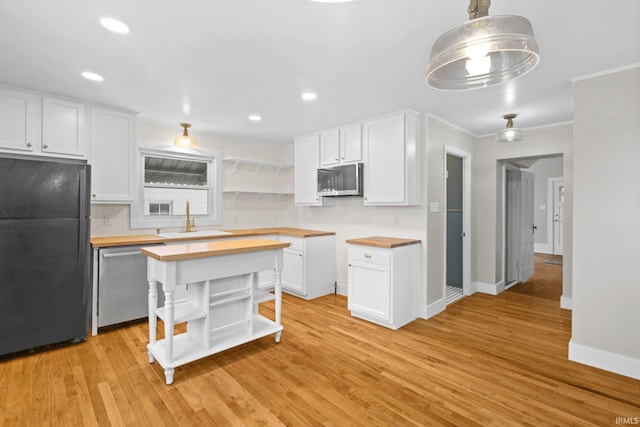 kitchen with pendant lighting, wooden counters, white cabinets, appliances with stainless steel finishes, and sink