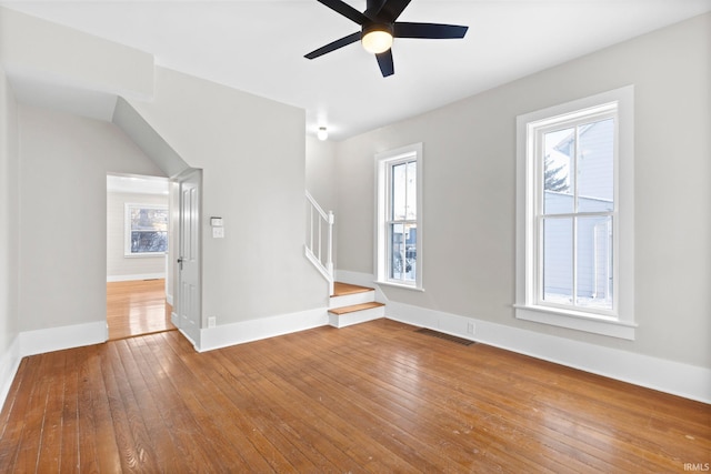 unfurnished living room with wood-type flooring, ceiling fan, and a wealth of natural light