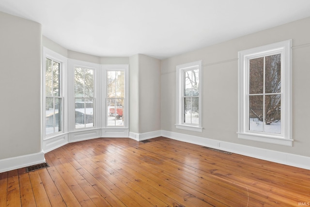 unfurnished room featuring a healthy amount of sunlight and hardwood / wood-style floors