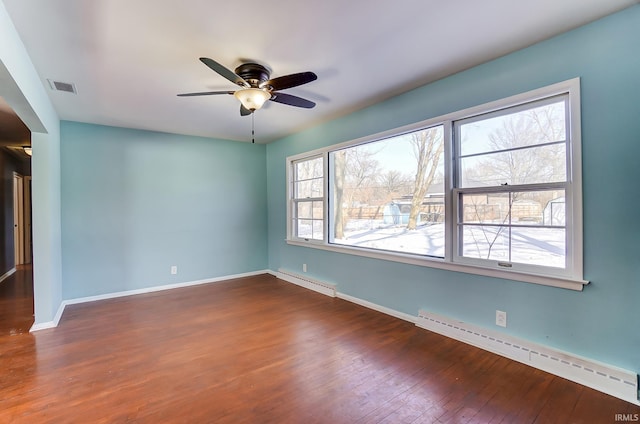 empty room featuring ceiling fan, baseboard heating, and dark hardwood / wood-style floors