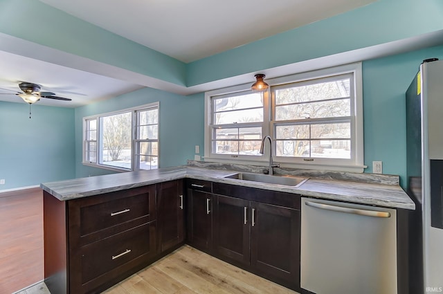 kitchen with stainless steel appliances, a healthy amount of sunlight, sink, kitchen peninsula, and light wood-type flooring