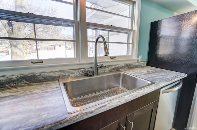 interior details with stainless steel dishwasher, black refrigerator, dark brown cabinets, and sink