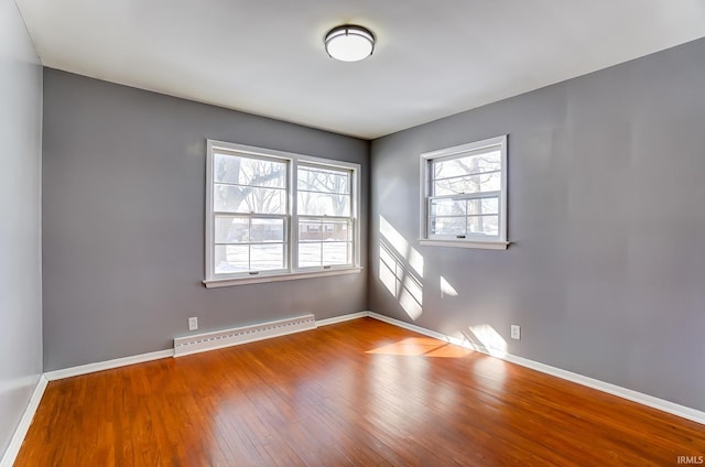 unfurnished room with wood-type flooring and a baseboard heating unit