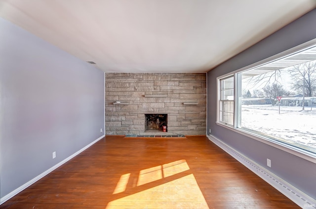 unfurnished living room featuring wood-type flooring and a stone fireplace