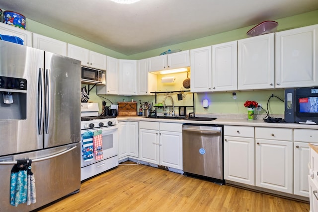 kitchen featuring appliances with stainless steel finishes, light hardwood / wood-style flooring, white cabinetry, and sink