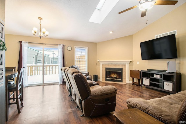 living room featuring vaulted ceiling, dark hardwood / wood-style floors, ceiling fan with notable chandelier, and a tiled fireplace