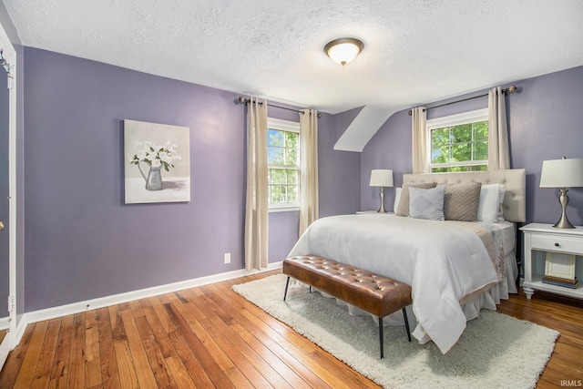 bedroom with multiple windows, a textured ceiling, and hardwood / wood-style floors