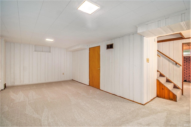 basement with light colored carpet and wood walls