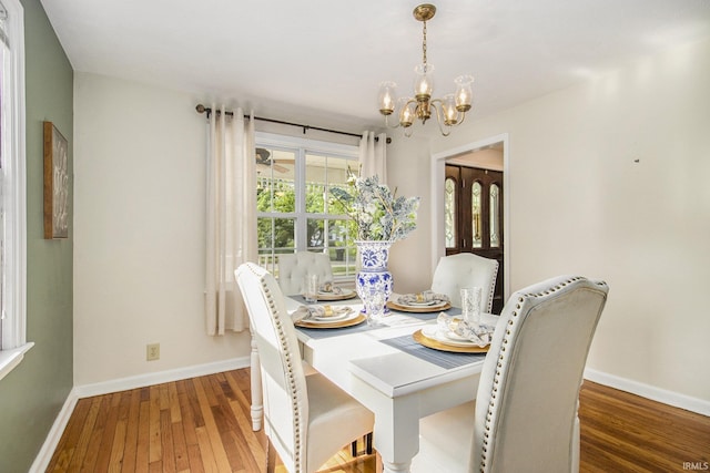 dining space with hardwood / wood-style floors and a chandelier