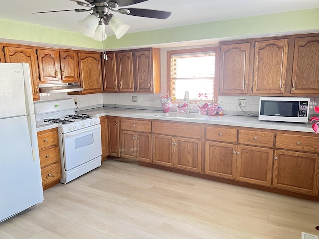 kitchen featuring white appliances, decorative backsplash, light wood-type flooring, ceiling fan, and sink