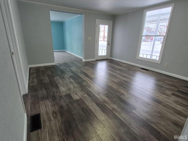 unfurnished room with dark hardwood / wood-style flooring, crown molding, and a wealth of natural light