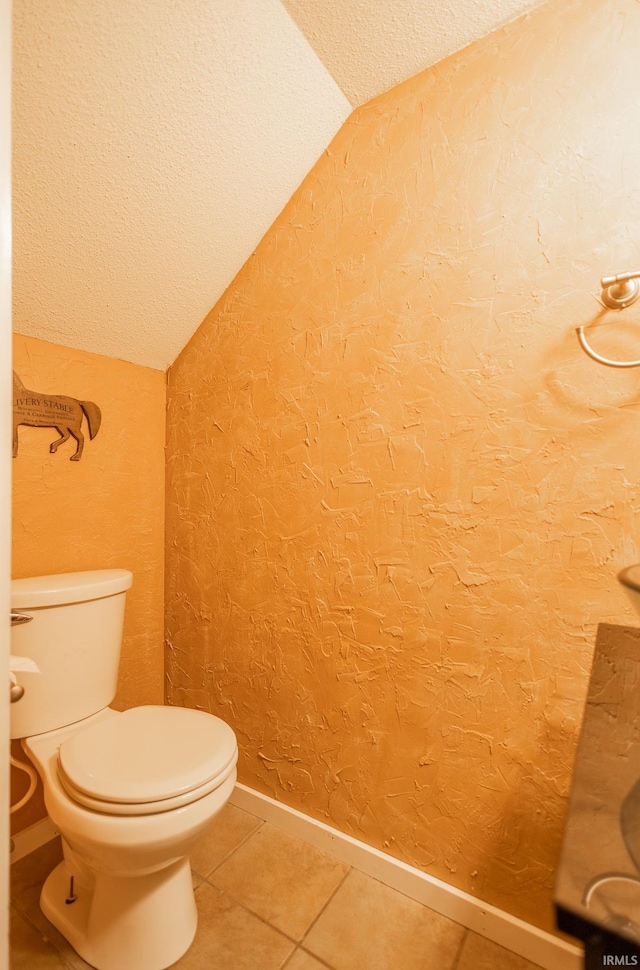 bathroom featuring tile patterned flooring, vaulted ceiling, and toilet