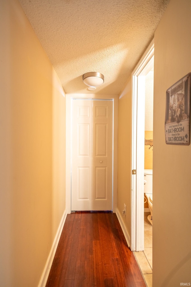 hall with a textured ceiling and hardwood / wood-style flooring