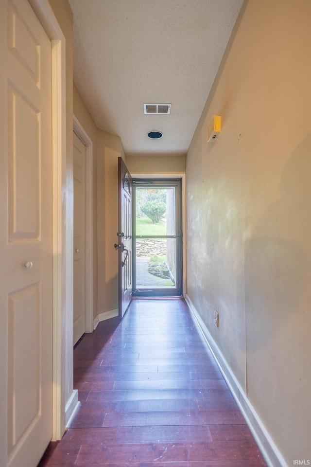 doorway featuring a textured ceiling and dark wood-type flooring