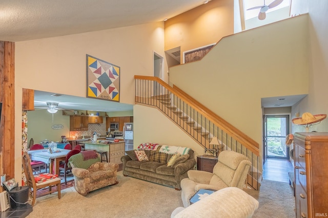 carpeted living room featuring a high ceiling and ceiling fan