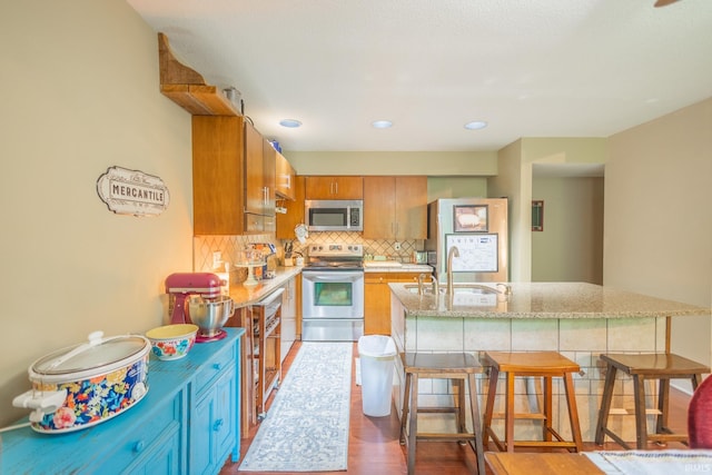 kitchen with decorative backsplash, appliances with stainless steel finishes, a kitchen breakfast bar, and sink