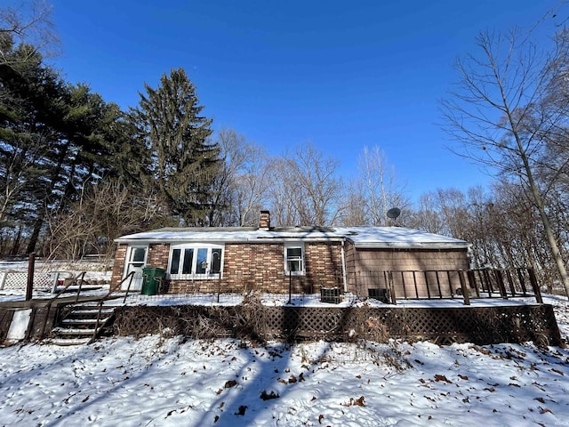 snow covered rear of property with a deck