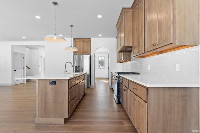 kitchen featuring hanging light fixtures, an island with sink, tasteful backsplash, appliances with stainless steel finishes, and sink