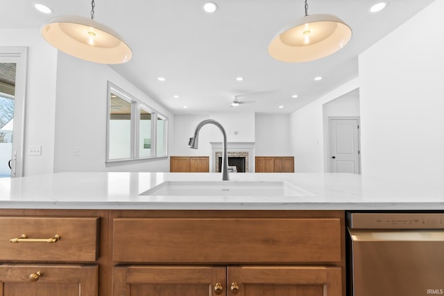 kitchen with sink, hanging light fixtures, stainless steel dishwasher, and light stone counters