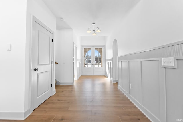 hall featuring a notable chandelier, french doors, and light hardwood / wood-style floors