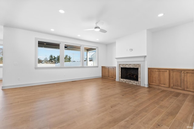 unfurnished living room featuring light hardwood / wood-style floors, ceiling fan, and a fireplace