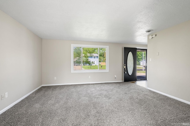 carpeted foyer entrance with a textured ceiling