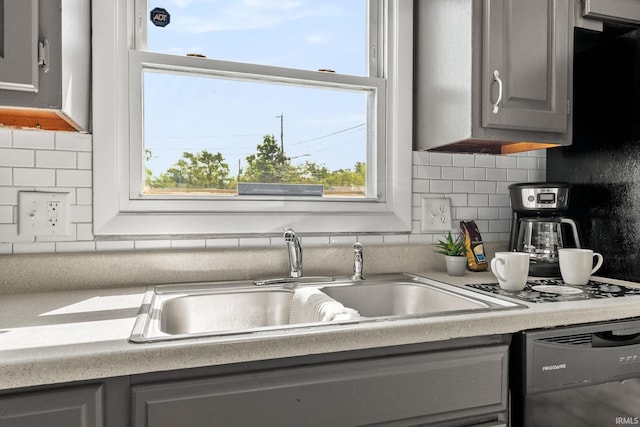 kitchen with decorative backsplash, gray cabinets, black dishwasher, and sink