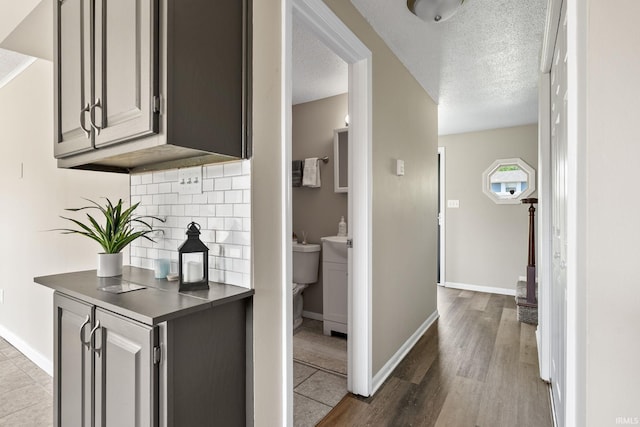 corridor with a textured ceiling and light hardwood / wood-style floors