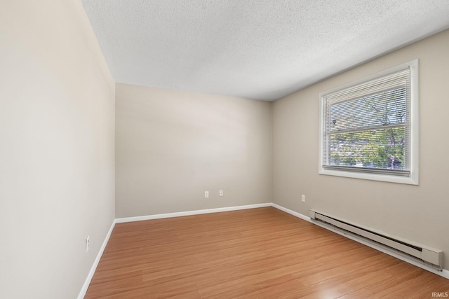 empty room featuring a textured ceiling, baseboard heating, and light hardwood / wood-style flooring