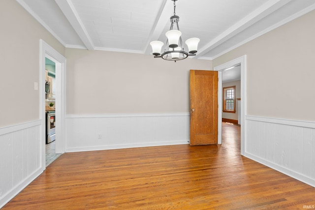 empty room featuring wood-type flooring, a chandelier, and crown molding