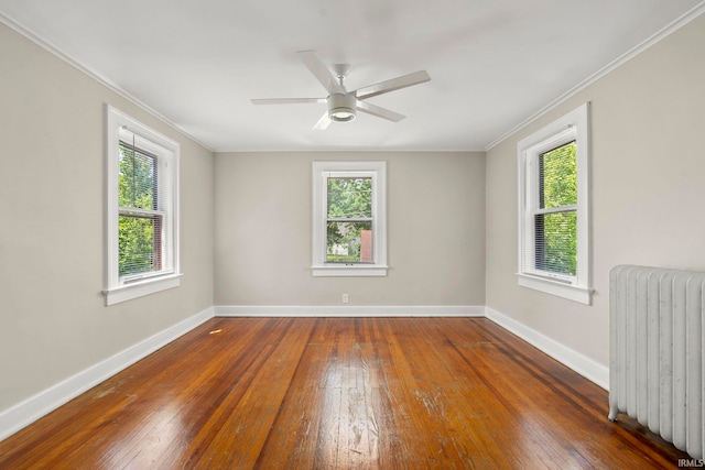 spare room featuring ceiling fan, radiator, dark hardwood / wood-style flooring, and plenty of natural light