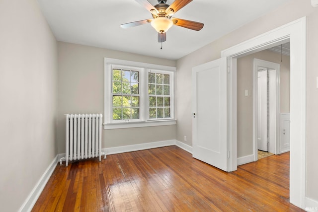 spare room with hardwood / wood-style flooring, ceiling fan, and radiator heating unit