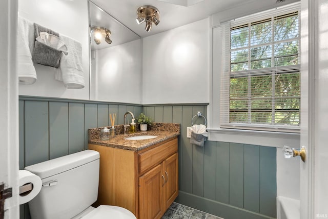 bathroom featuring toilet, wood walls, and vanity