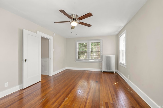 unfurnished room with ceiling fan, radiator, and dark hardwood / wood-style floors