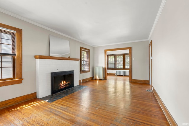 unfurnished living room with a fireplace, ornamental molding, radiator, and hardwood / wood-style flooring