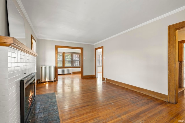 unfurnished living room with ornamental molding, radiator heating unit, a fireplace, and wood-type flooring